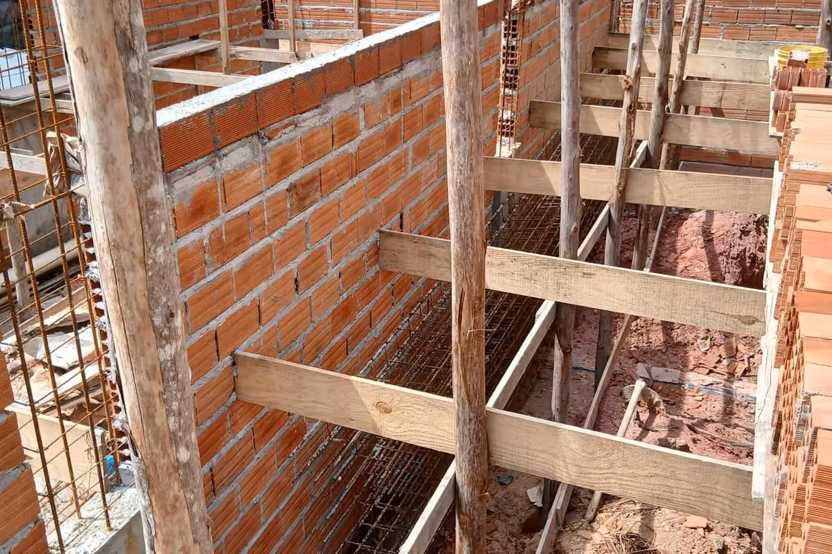 Red brick walls under repair, braced with timber props and cross members