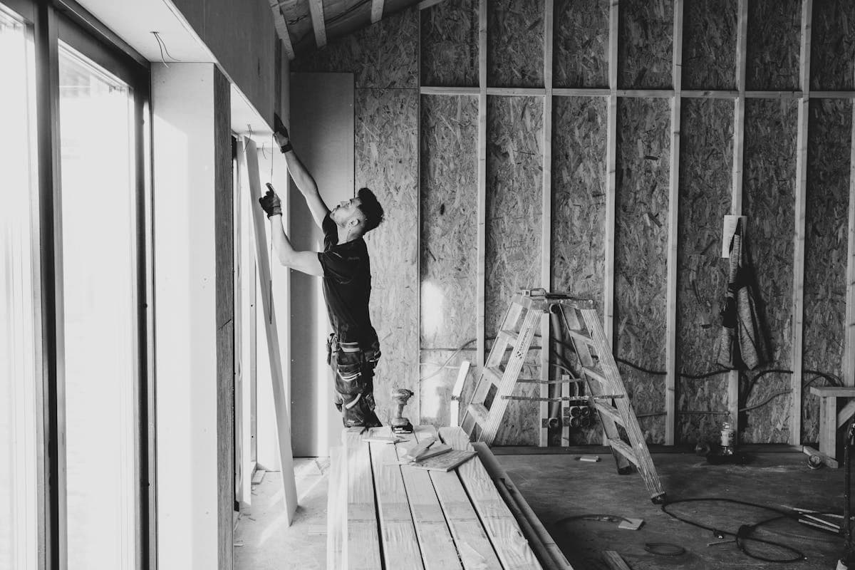 Carpenter working from approved plans inside a new build
