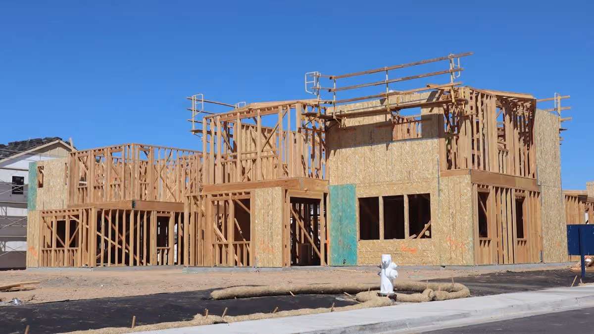 Two-storey timber frames with scaffolding against a clear sky
