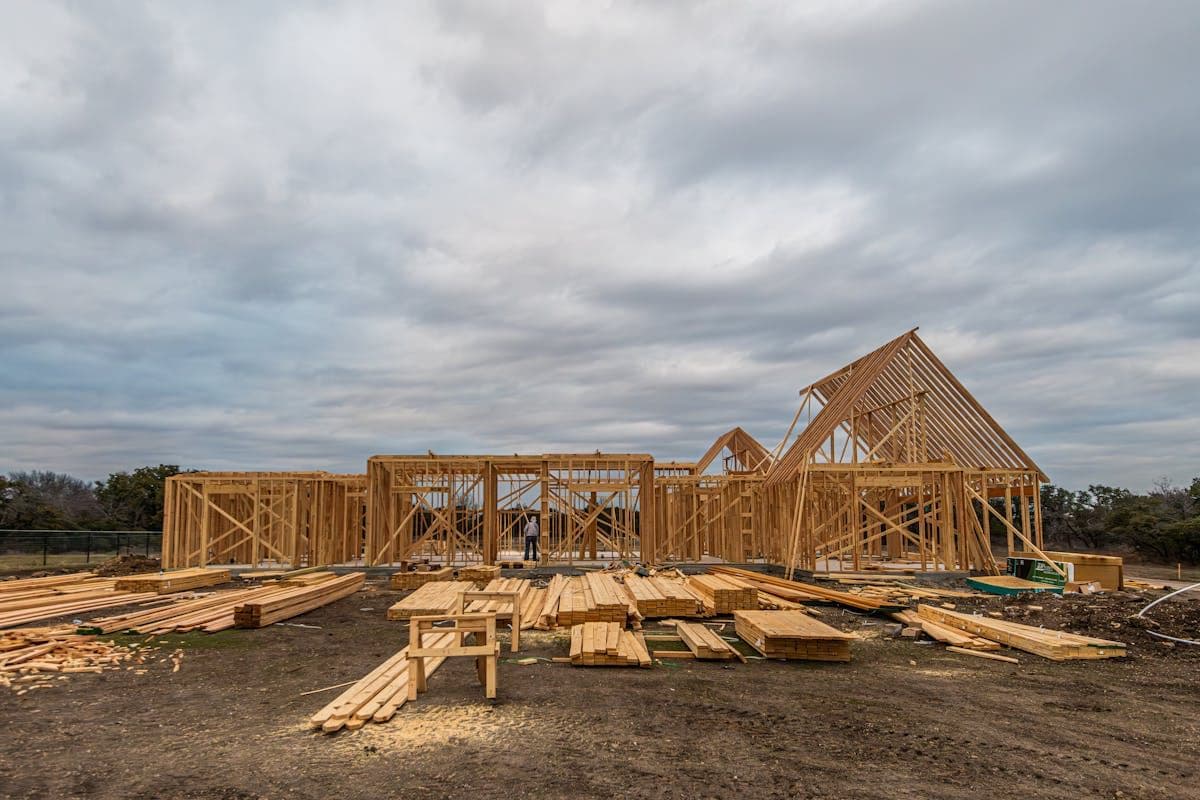 Timber house frame standing on a concrete slab in an open grassy field