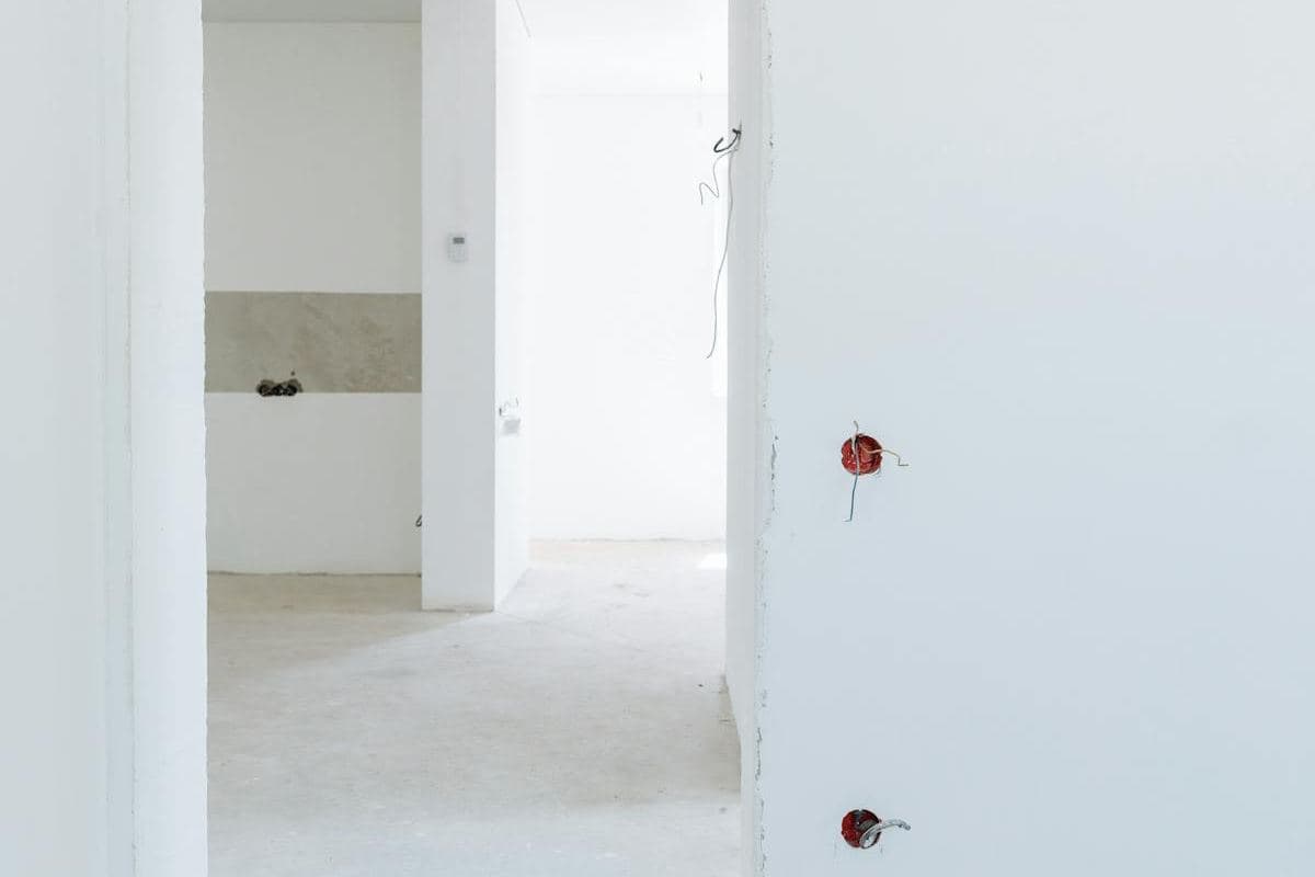 Narrow white-walled hallway opening into rooms, freshly lined and ready for finishing