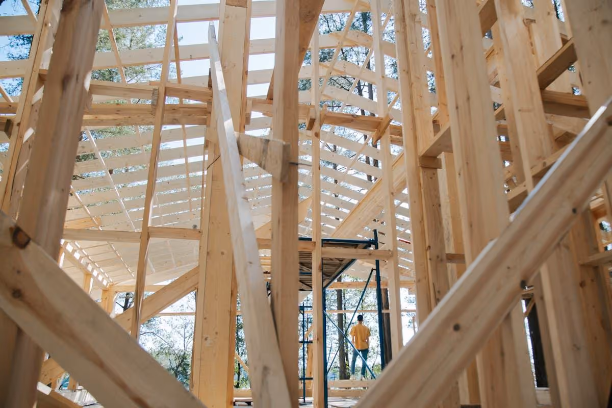 Carpenter working on a house frame with tall eucalypts visible behind the structure
