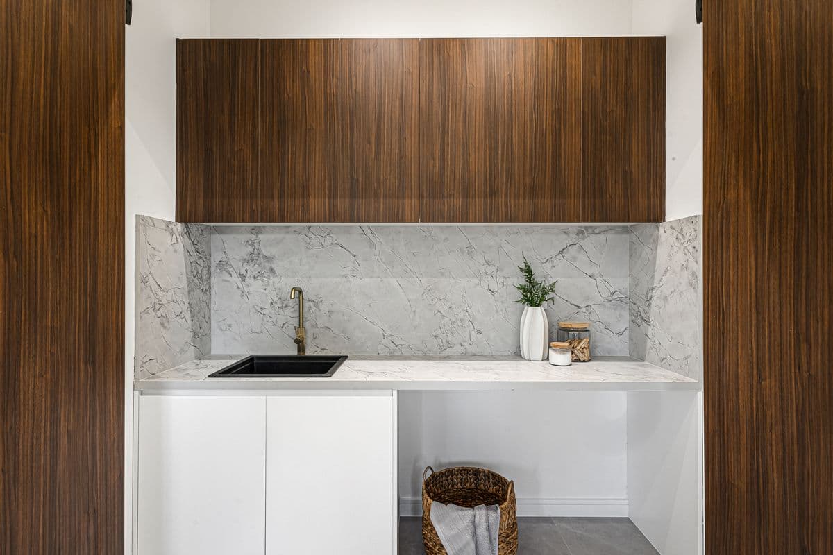 Laundry with white cabinetry, a deep sink and a tiled splashback