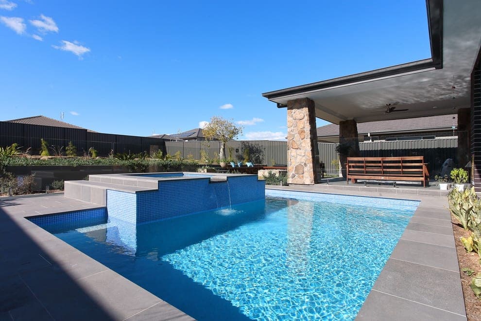 Luxury outdoor living space with pool, fireplace and undercover dining used as a custom home reference for Carramar