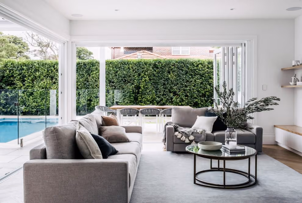Open-plan living room with grey sofa opening through sliding doors to a covered alfresco