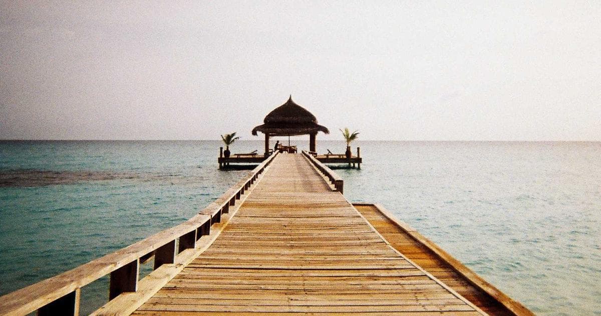 Long timber jetty stretching over calm water to a small pavilion