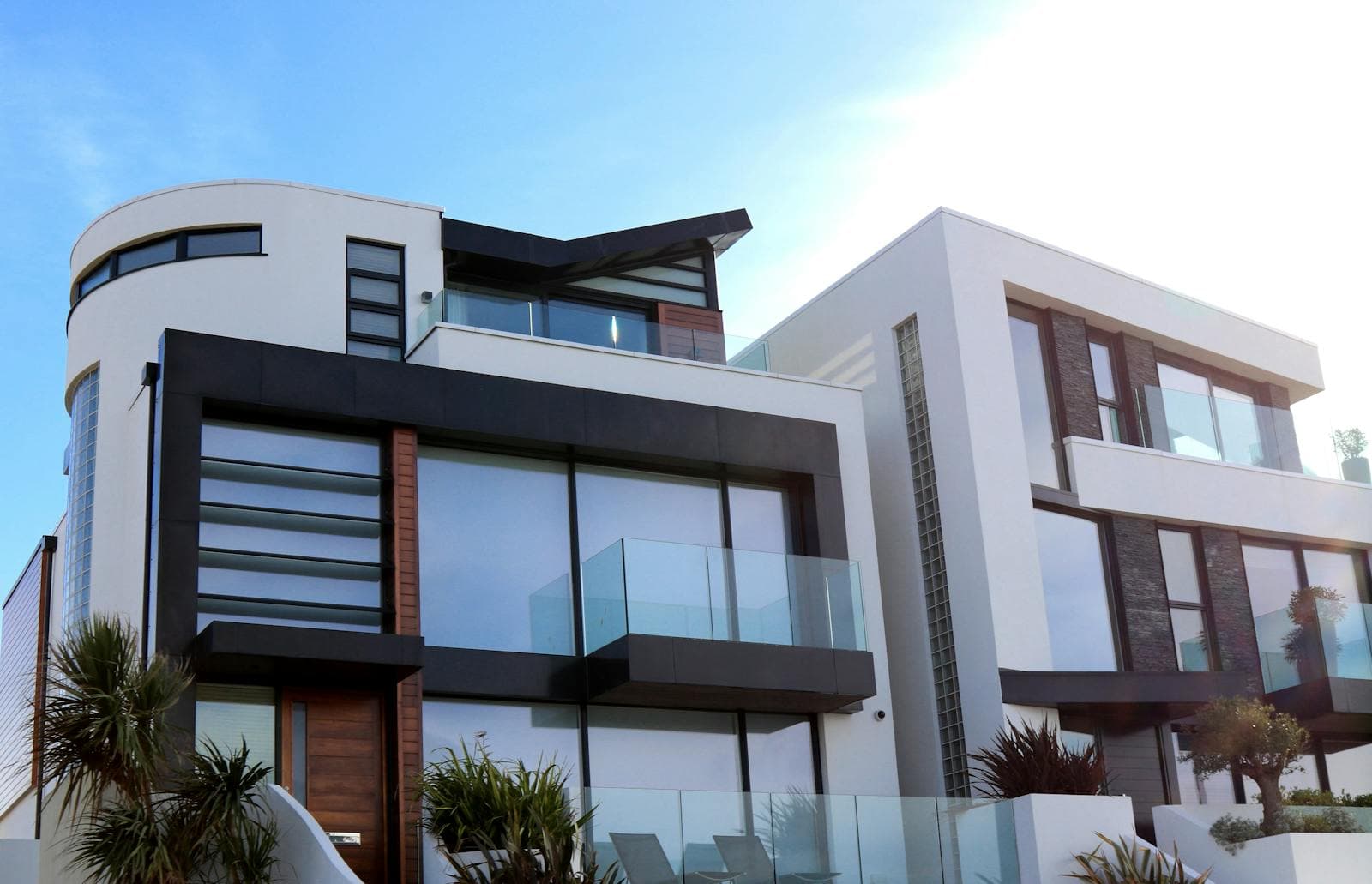 Pair of contemporary multi-level homes with balconies and large glazing under a clear sky