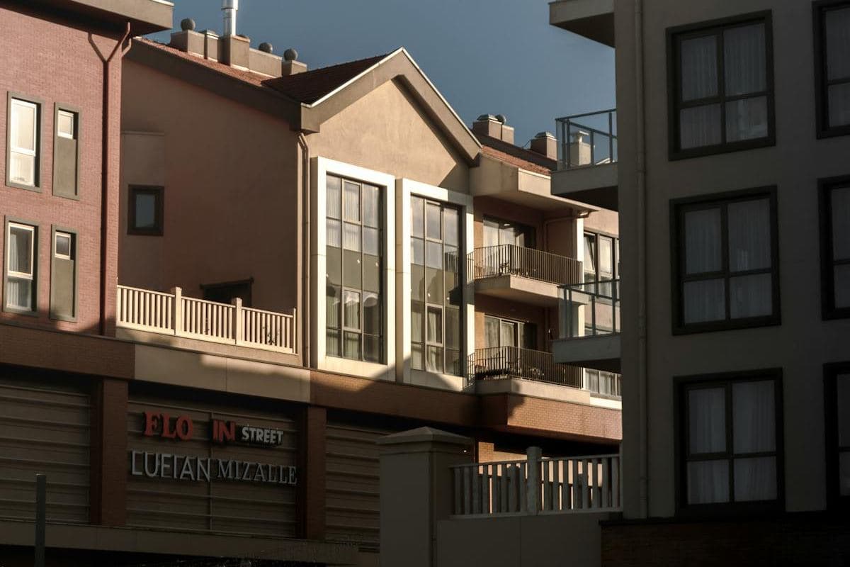 Attached brick and render homes with balconies and gabled rooflines along a residential street