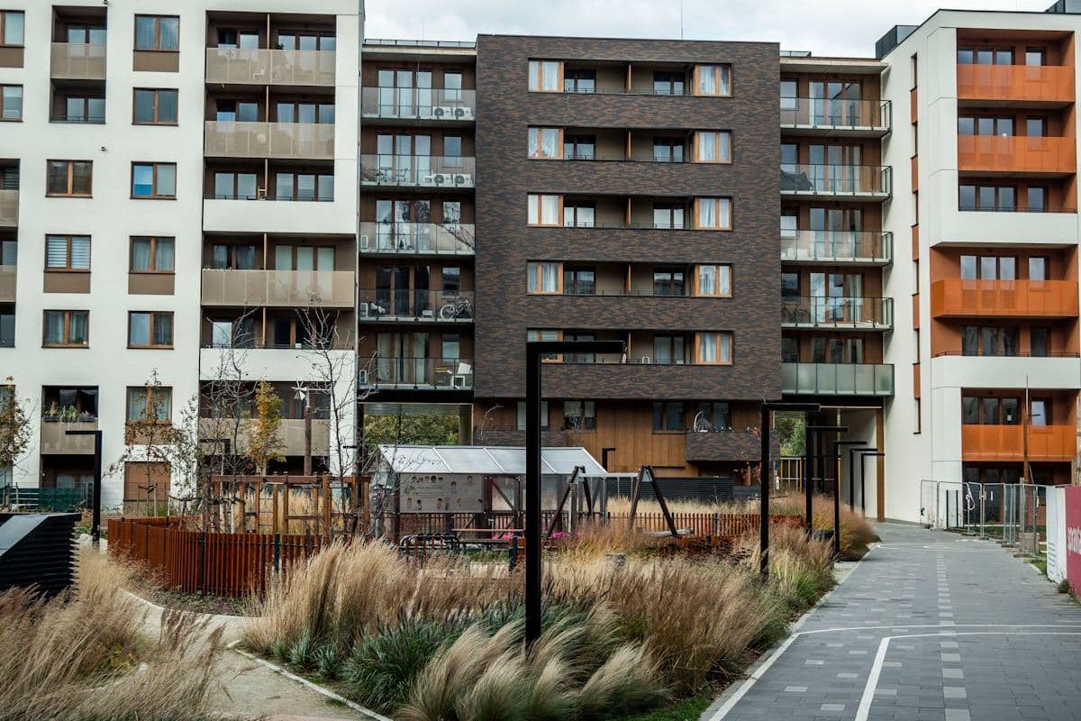Landscaped courtyard between mid-rise apartment buildings with a paved walkway