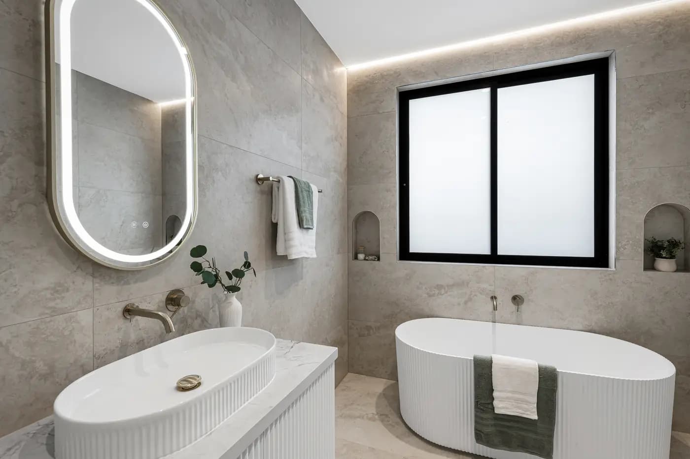 Bathroom with freestanding bath, fluted vanity and arched mirror