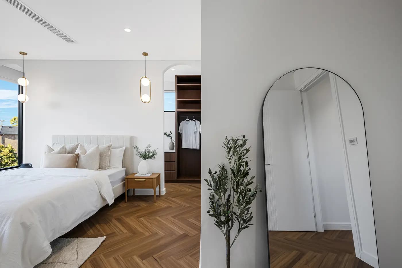 Renovated bedroom with an arched robe niche, herringbone timber floor and soft neutral bedding