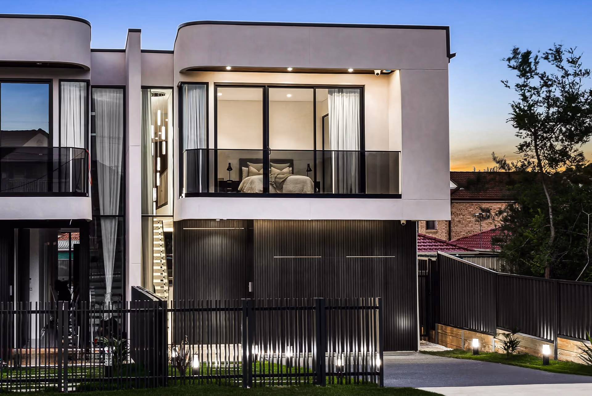 Curved facade and warmly lit interiors of Buildana’s Smart Street home in Fairfield Heights