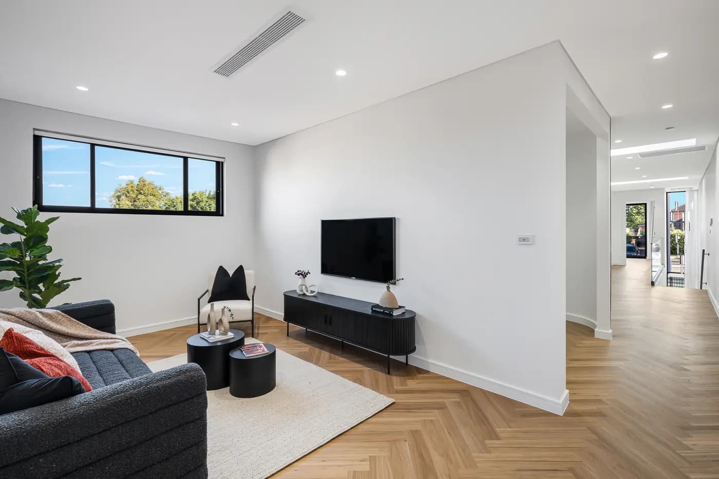 Family room with herringbone timber floor and television wall