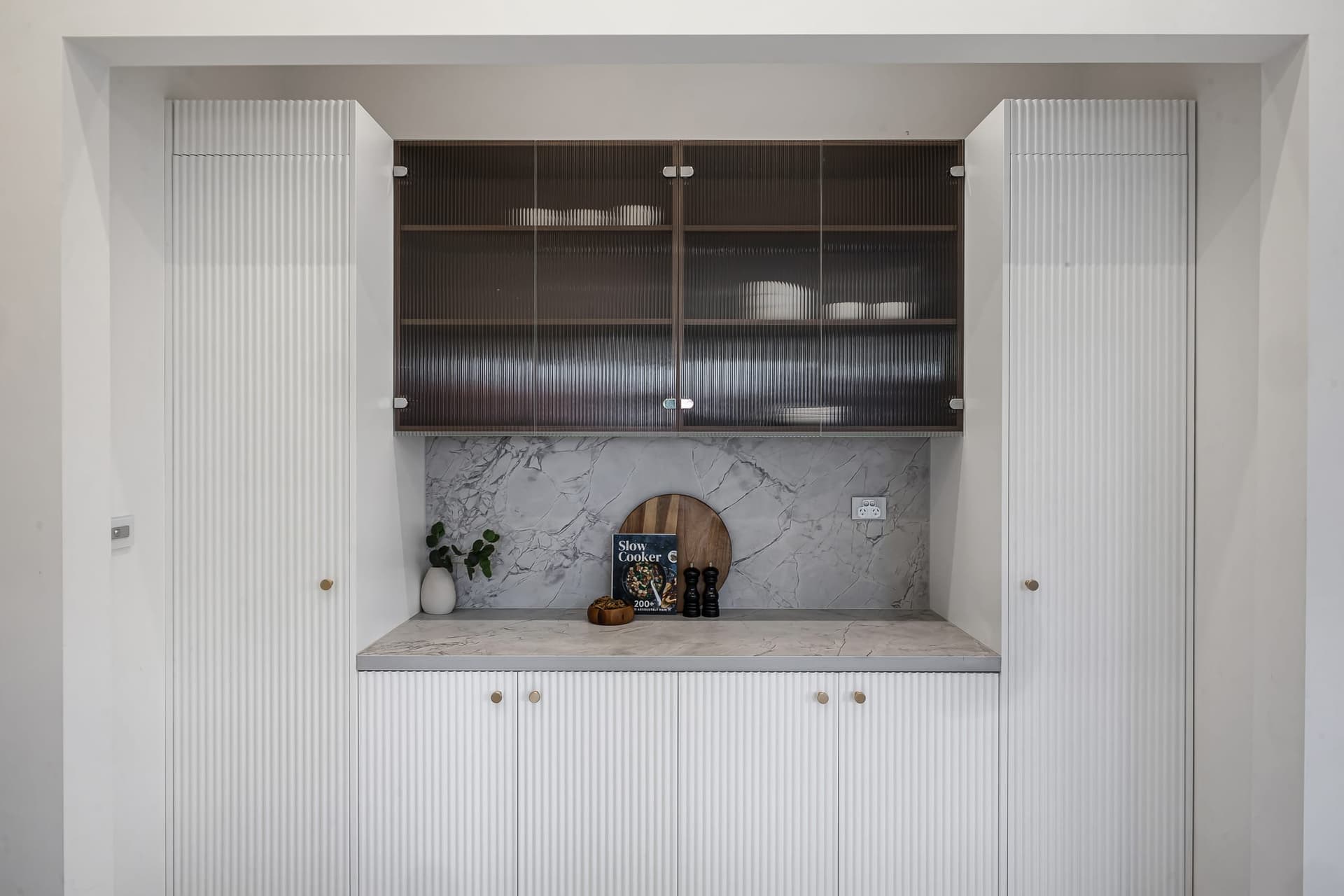 Kitchen servery window with timber joinery opening onto an outdoor area