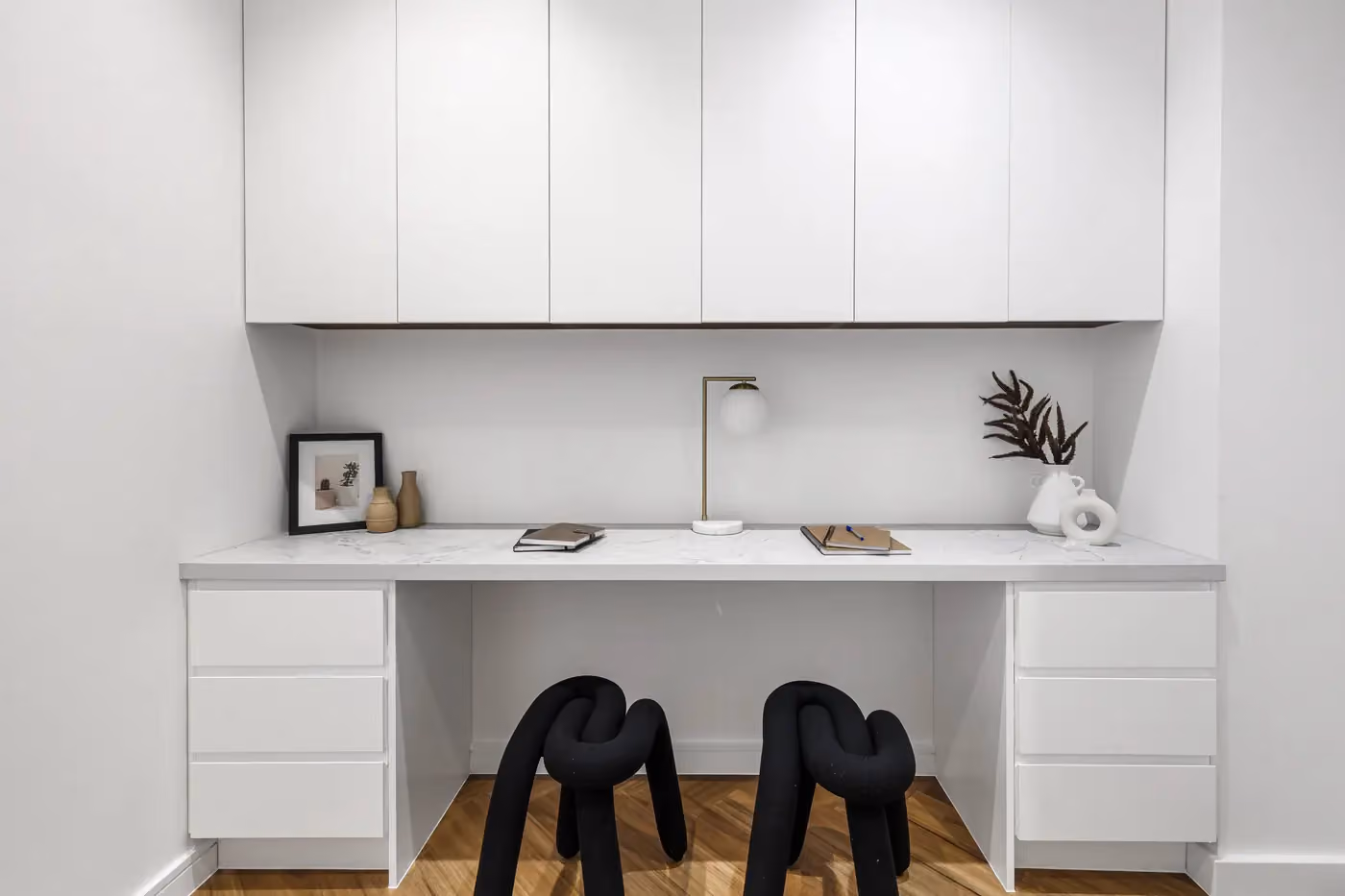 Built-in study with white joinery, two desk chairs and neatly arranged shelving